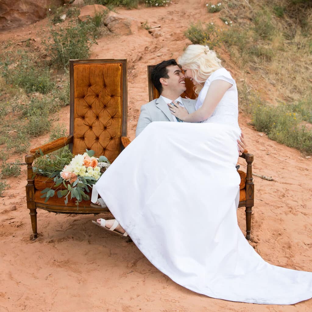 bride and groom snuggling on orange chair in red rock canyon