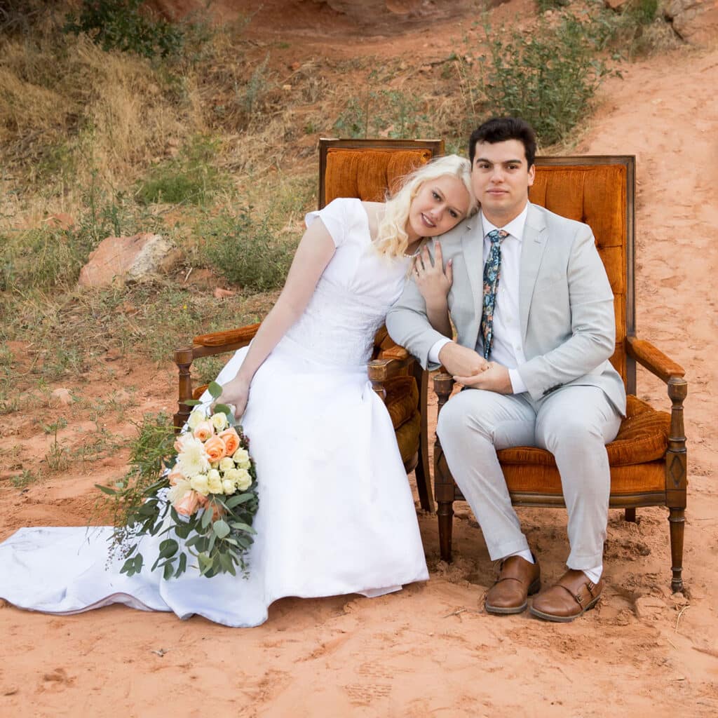 bride and groom on orange chairs in red rock canyon