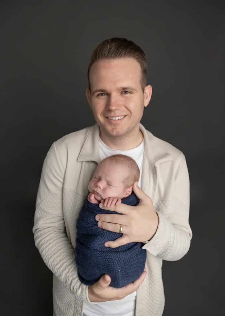 dad holding newborn baby boy in blue wrap