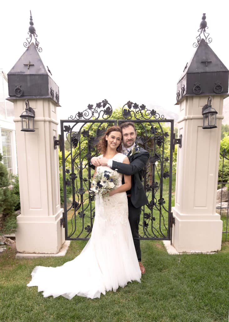 bride and groom in front of black intricate gate