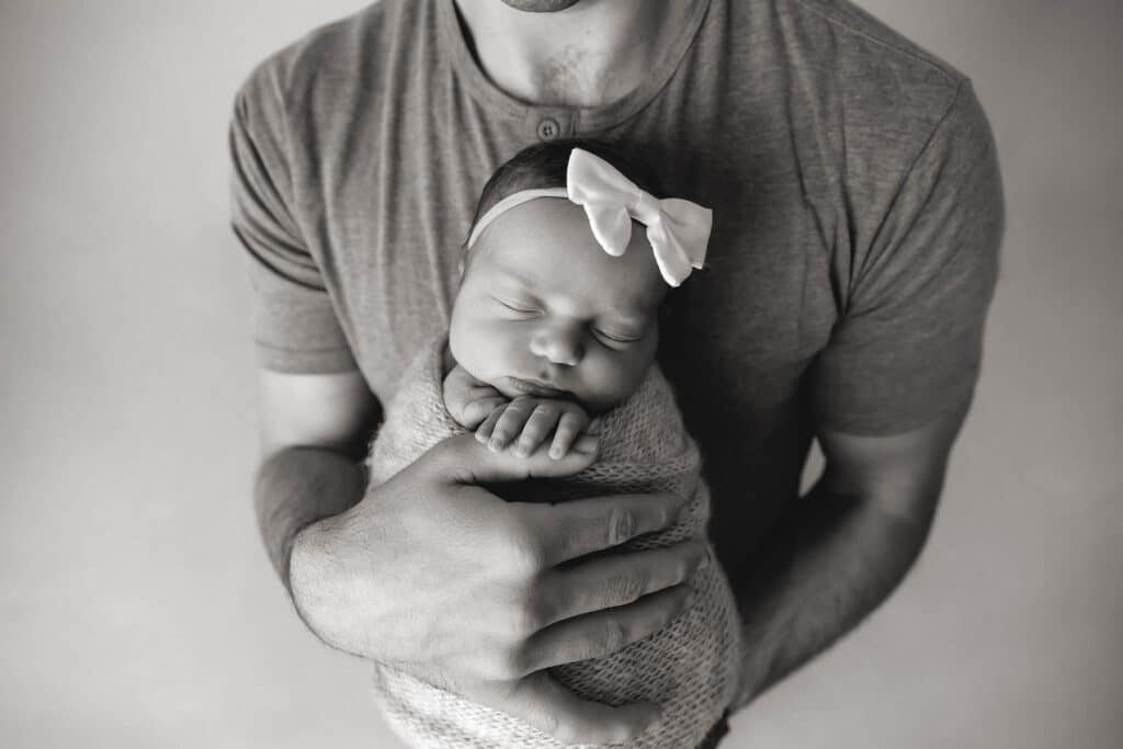 dad holding newborn girl closeup in black and white
