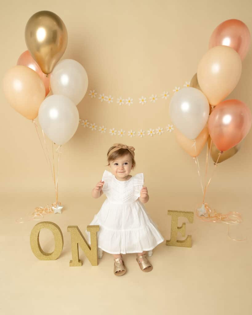 first birthday girl with balloons and one letters
