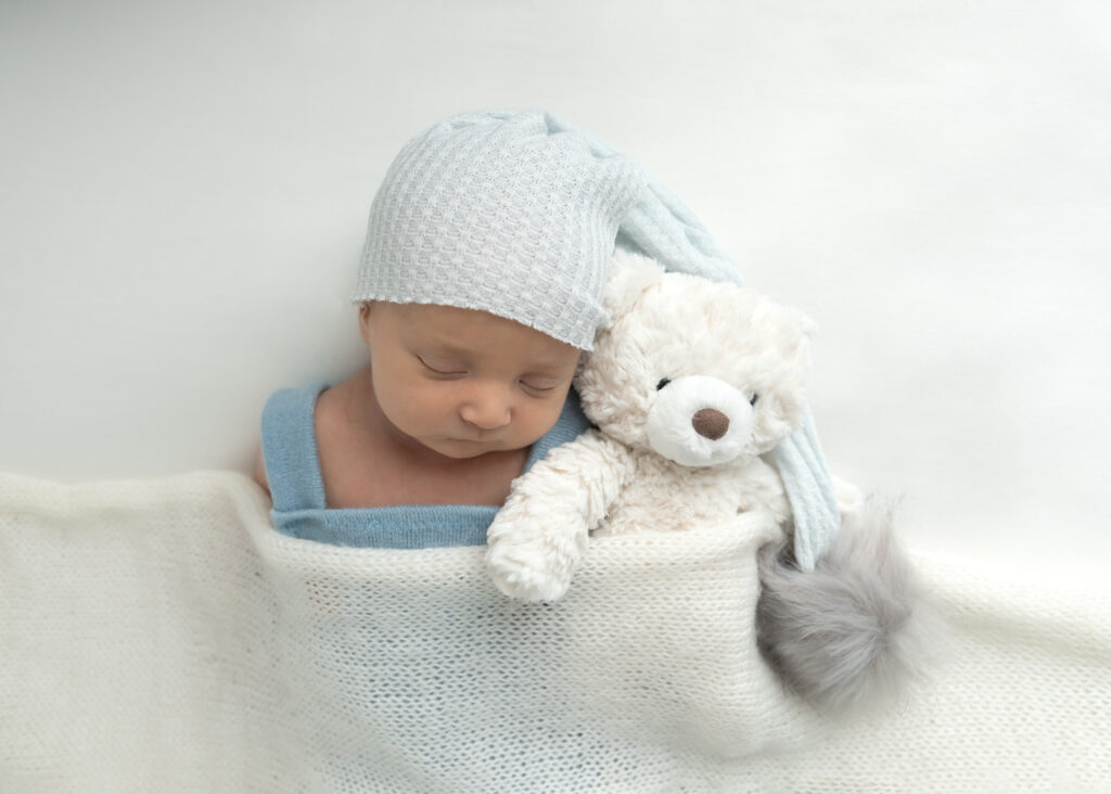 utah county newborn photographer newborn session with white teddy bear and baby in blue overalls