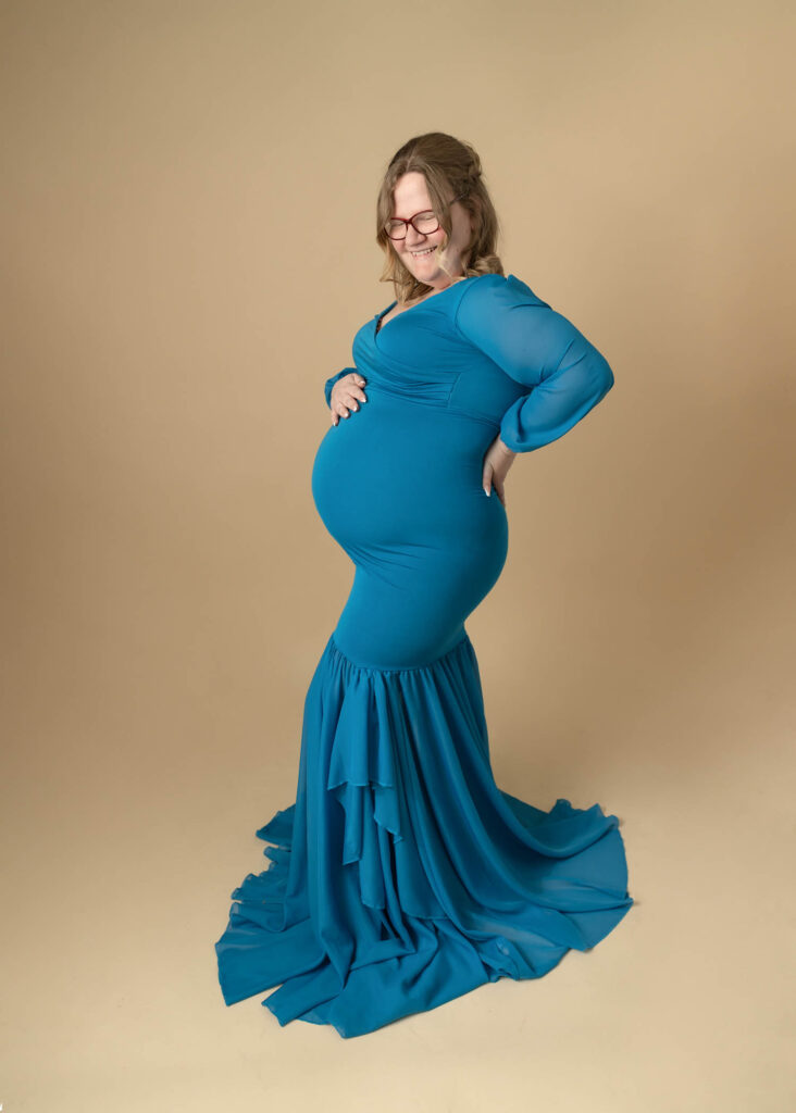 pregnant mom in beautiful blue gown on tan backdrop