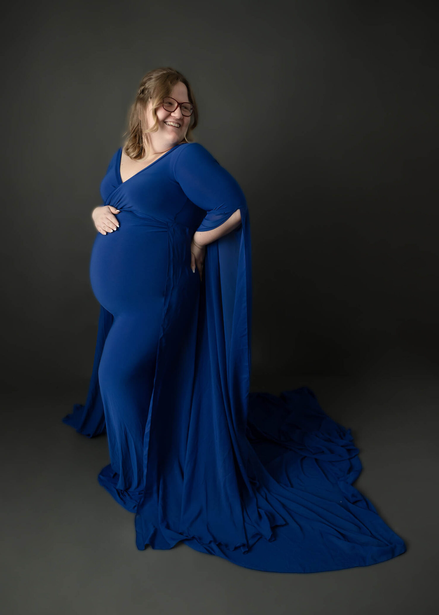 pregnant mom in royal blue maternity gown on gray backdrop