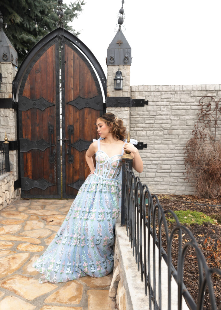 bride in front of a castle gate leaning on a fence