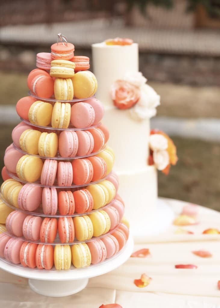 macrons in pink and yellow in front of a wedding cake