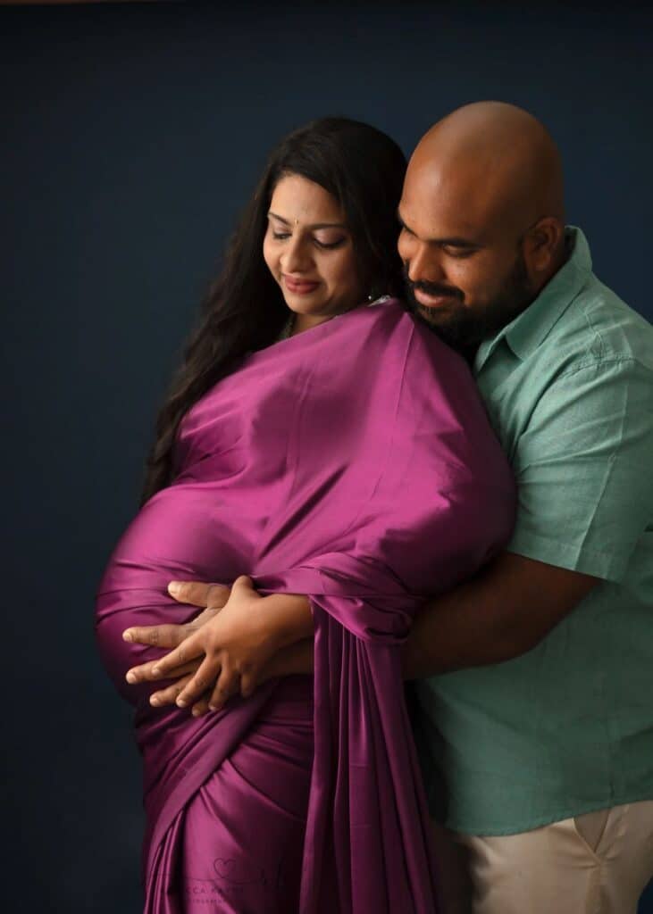 pregnant mom in purple gown snuggling with dad