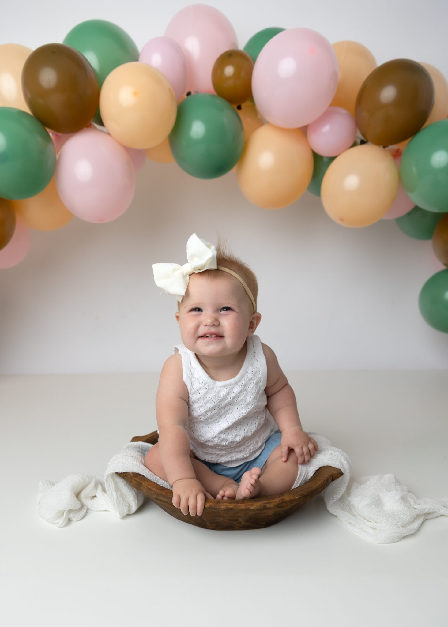 Utah County child photographer girl sitting in bowl smiling at camera